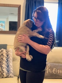 a woman holding a puppy in a living room