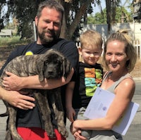 a man and woman holding a dog and papers