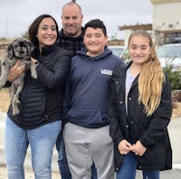 a family is posing for a picture with their dog